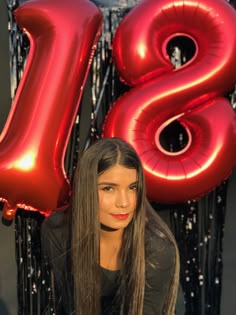 a woman with long hair standing in front of balloons and the number 28 on it