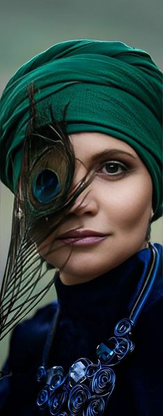 a woman wearing a green turban with peacock feathers on it's head