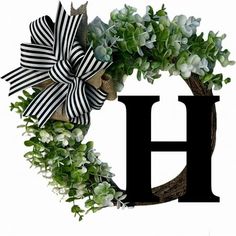 the letter h is decorated with green and white flowers, including an artificial wreath that has been placed on top of it