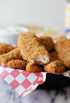 some fried food is in a basket on a table with checkered paper around it