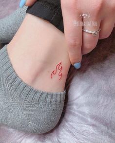 a woman's foot with a small tattoo on her left side and the word yoga written in red ink