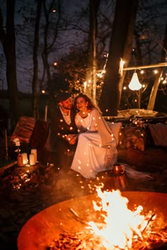 a man and woman sitting in front of a fire pit