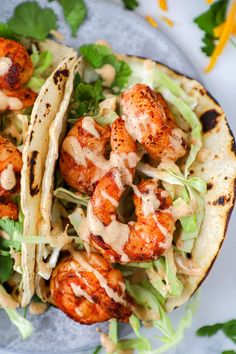 shrimp tacos with cilantro sauce and lettuce on a blue plate