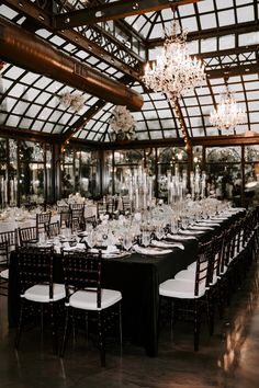 a large dining room set up with black and white table cloths, chandeliers and chairs