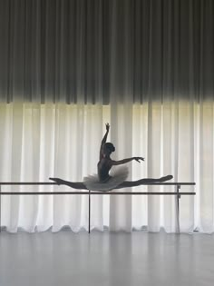 a ballerina is sitting on the edge of a ballet pole in front of curtains