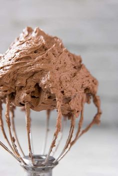 a whisk filled with chocolate frosting sitting on top of a table