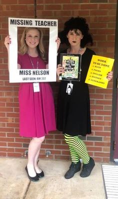 two women standing next to each other holding signs