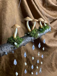 three mushrooms on a branch with moss and crystals hanging from it