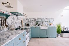 a kitchen with blue cabinets and marble counter tops