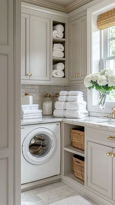 a washer and dryer in a room with lots of white towels on the shelves