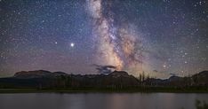 the night sky is filled with stars and bright lights, as seen over a body of water