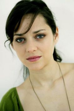 a close up of a person wearing a necklace and looking at the camera with a serious look on her face