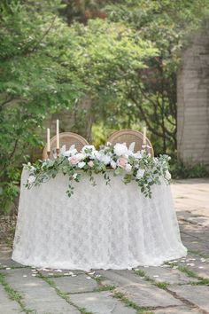 a table with flowers and candles is set up for an outdoor wedding reception in the garden