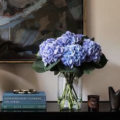 a vase filled with blue flowers sitting on top of a table next to two books