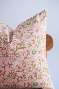 a pink pillow with green and white flowers on it