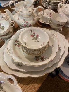 a table topped with lots of white dishes and plates covered in floral designs on them