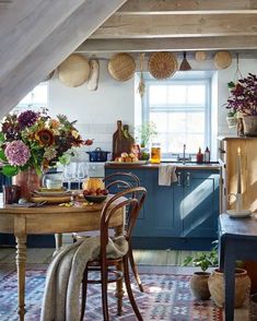 a kitchen with blue cabinets and an old wooden table in the center is filled with flowers