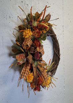 a wreath hanging on the side of a wall with dried flowers and leaves around it