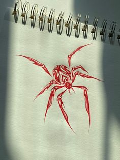 a drawing of a red spider on a white sheet of paper with spirals attached to it