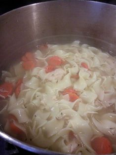 a pot filled with pasta and carrots on top of a stove