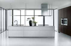 a modern kitchen with white counter tops and stainless steel appliances on the wall, along with large windows