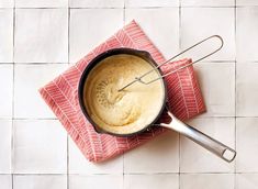 a pan with some food in it on a red and white cloth next to a spoon