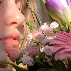 a close up of a person smelling flowers