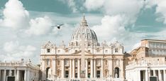 a large building with a bird flying in the sky above it and people walking around