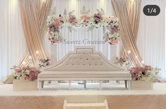 a bed sitting on top of a white table under a flower filled arch with flowers