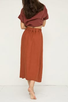 the back view of a woman wearing an orange skirt and brown top with her hands on her hips