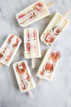 five popsicles with different toppings sitting on top of a marble countertop next to each other