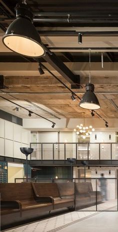 the interior of an office building with lots of light fixtures and wooden benches in front of them