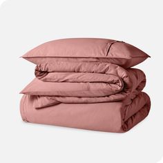 three pillows stacked on top of each other in front of a white background with pink sheets