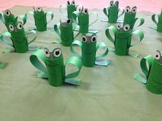 green paper cups with googly eyes are sitting on a table