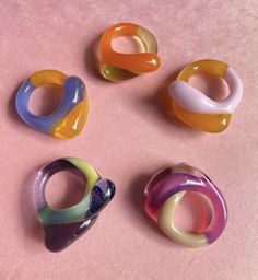 four different colored rings sitting on top of a pink surface