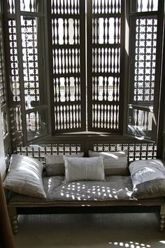 a day bed with pillows on it in front of a large open window that looks out onto the street