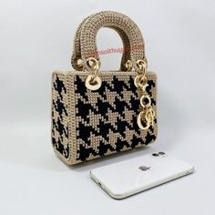 a cell phone sitting next to a purse on top of a white table with a black and beige pattern