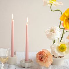 three candles are lit on a table with flowers