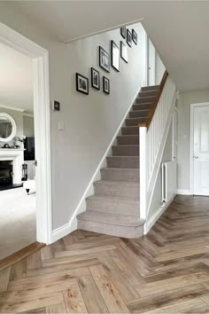 a staircase with pictures on the wall next to it and wooden flooring in front