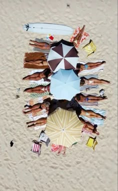 a group of people standing on top of a sandy beach under an umbrella in the sand