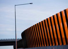 a traffic light on a pole next to a large orange structure with black and white stripes