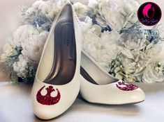 pair of white shoes with star wars logo on them and flowers in the back ground