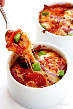 two white bowls filled with different types of pizza and one has a spoon in it