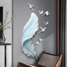 a living room with grey walls and white birds on the wall, while a chair sits in front of it