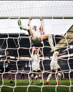 the soccer player is jumping up to try and block the ball from going into the net