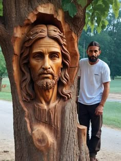 a man standing next to a carved face on a tree