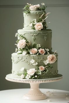 a three tiered green cake with flowers on the top and sides, sitting on a table