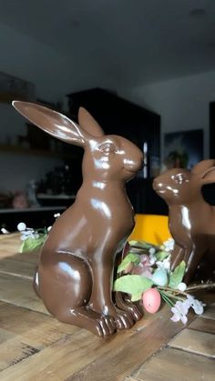 two chocolate rabbits sitting on top of a wooden table