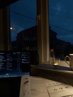 a laptop computer sitting on top of a desk next to a cup and saucer