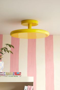 a pink and white striped wall with a yellow light hanging from it's ceiling